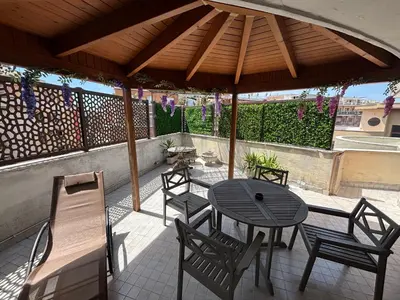 a patio with a table and chairs under a wooden umbrella at Last floor Aurelio Vaticano in Rome
