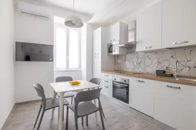 a kitchen with white cabinets and a table and chairs at Domus Ponte Lungo in Rome