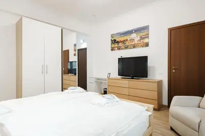 a white bedroom with a bed and a television at Gioele's Apartment in Rome