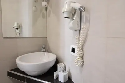 a bathroom with a white sink and a phone on the wall at Maison Maneli in Rome