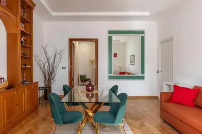 a living room with a glass table and green chairs at GuestHost - Bright Apartment X4 along the Tevere! in Rome
