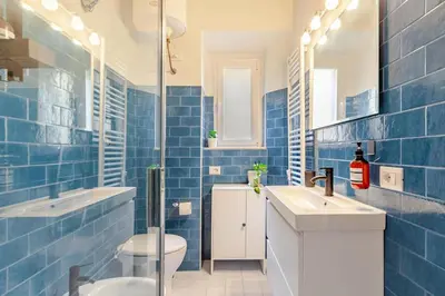 a blue tiled bathroom with two sinks and a toilet at RL Apartment in Rome