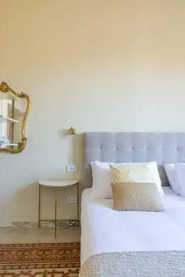 a bedroom with a bed with a mirror and a table at Stylish 3BR between Vatican & City Center in Rome