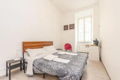 a bedroom with a bed and a red chair at San Pietro View Boutique Rooms in Rome