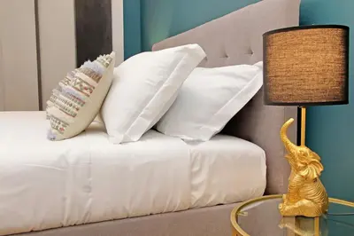 a bed with white pillows and a table with a lamp at 4BNB - Flaminio Modern Apartment in Rome