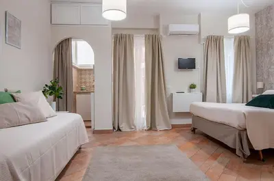 a white bedroom with two beds and a television at St Peter Vatican Lovely Apartment & Patio, Rome in Rome