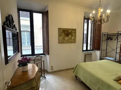 a bedroom with a bed and a table and windows at Borgo Pio Vatican in Rome