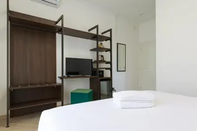 a bedroom with a white bed and a tv at Villa Aurora Rooms in Rome