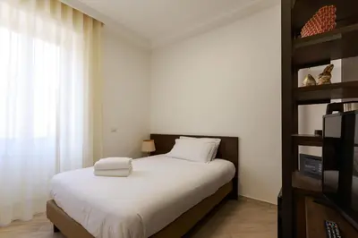 a bedroom with a bed with white sheets and a window at Villa Aurora Rooms in Rome