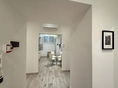 a white room with a table and a kitchen at Appartamento stazione trastevere in Rome