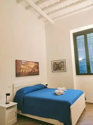 a white bedroom with a blue bed and a window at Casa Beatrice, Trastevere in Rome