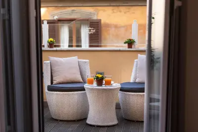 a balcony with wicker chairs and a table with drinks at Relais Monti in Rome