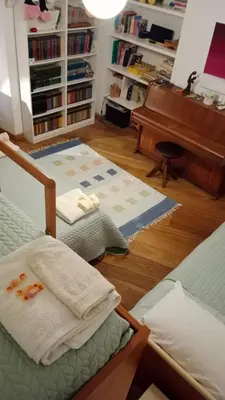 a living room with two beds and a piano at Private room by an Italian family - A unique experience close to Colosseum, the Roman Forum and Basilica Saint Mary Major in Rome