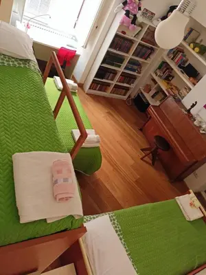 a living room with a green couch and a desk at Private room by an Italian family - A unique experience close to Colosseum, the Roman Forum and Basilica Saint Mary Major in Rome