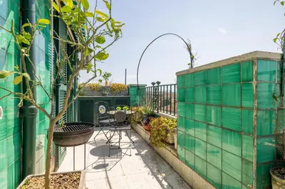 a balcony with a green fence and a table and chairs at Dolce Vita Penthouse in Rome
