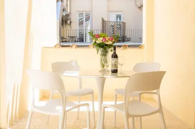 a table with white chairs and a vase of flowers at Amazing Via del Corso 277 Suites in Rome