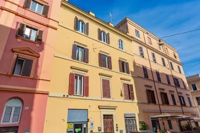 a yellow building with red shutters on a street at Glam Nest & Garden Colosseum in Rome