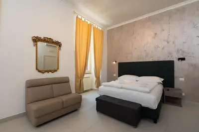 a bedroom with a bed and a chair and a mirror at Alida Rooms in Rome