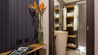 a vase of flowers on a table in a bathroom at QT Suites Roma in Rome