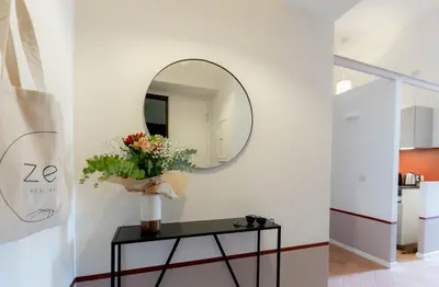 a mirror on a wall next to a table with flowers at Colosseum suites apartment - Zen 22 in Rome