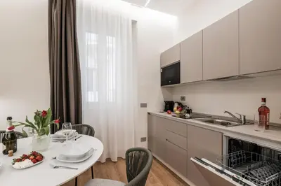 a white kitchen with a white table and chairs at The Best Rent - Atmosphere and romance: one-bedroom apartment just steps from the Colosseum in Rome