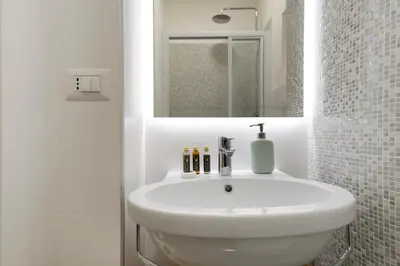 a bathroom with a white sink and a mirror at Elegantis Trastevere Modern Apartment - Comfort in Rome Most Charming District in Rome