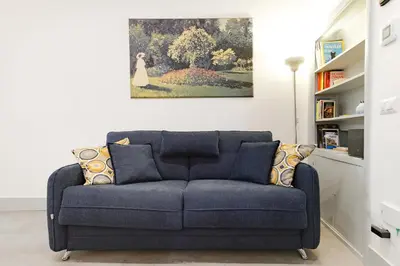 a blue couch in a living room with a painting on the wall at Elegantis Trastevere Modern Apartment - Comfort in Rome Most Charming District in Rome