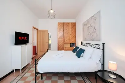 a bedroom with a white bed and a tv at Tuscolana Station - 10 minutes from Metro A in Rome