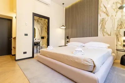 a bedroom with a large bed with white sheets and pillows at Minerva Boutique Suites in Rome