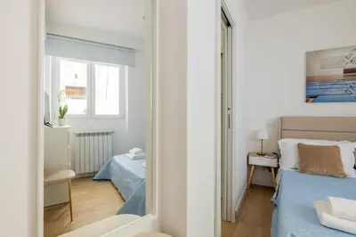 a white bedroom with a bed and a mirror at NOSTROMONDO-Elegant Suite with patio in Monti Parioli in Rome