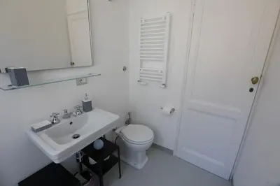 a white bathroom with a toilet and a sink at Colosseum Panoramic Terrace in Rome