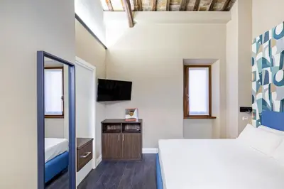 a bedroom with a bed and a tv and a mirror at Maison dei Greci in Rome