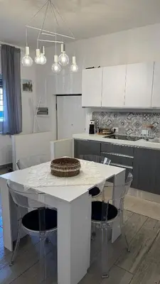a kitchen with a white table with chairs and a counter at Angoletto di Mirtilla in Rome