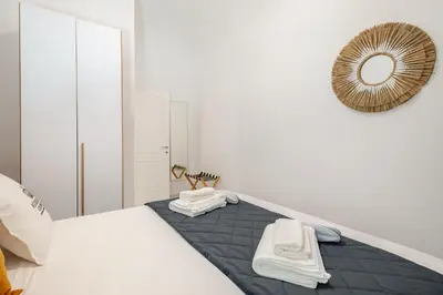 a white bedroom with a bed and a mirror at Aurelian Crown Central Rome in Rome