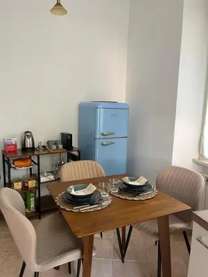 a dining room table with chairs and a blue refrigerator at Pigneto Cosmo House in Rome