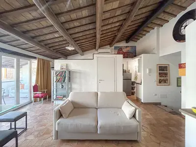 a living room with a white couch and a kitchen at Attic Castel Sant'Angelo - Pantheon in Rome