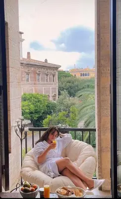a woman laying in a bed on a balcony at Terrazza Marco Antonio Luxury Suite in Rome