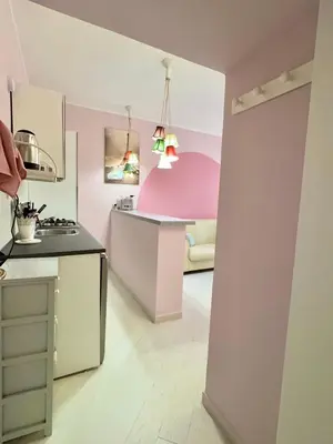 a kitchen with pink and white walls and a table at Vacanze Romane a San Giovanni in Rome