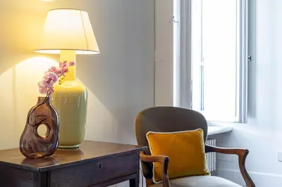 a table with a vase and a lamp and a chair at iFlat Monti Life with Elegance, Comfort and Beauty in Rome
