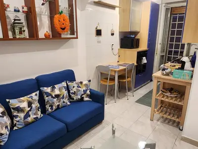 a living room with a blue couch and a kitchen at La casetta di Marco in Rome
