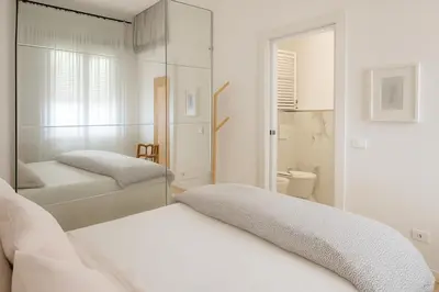 a white bedroom with two beds and a mirror at Casetta Beatrice Cozy Flat near Vatican in Rome