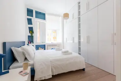 a white and blue bedroom with a bed and a window at Quiet retreat in Trastevere - ZENO 45 in Rome