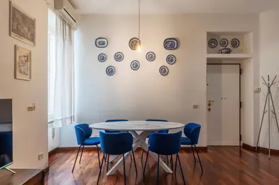 a dining room with a table and blue chairs at Piazza Alessandria - FromHometoRome in Rome