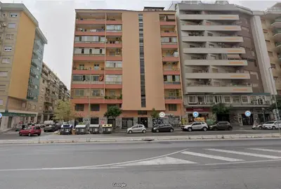 a large building with cars parked in a parking lot at Backhaus Tiburtina in Rome