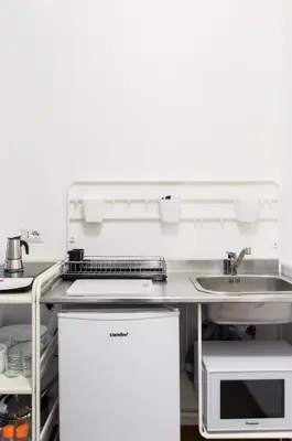 a white kitchen with a sink and a counter at House in the shopping street at Trastevere station in Rome