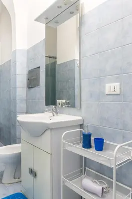 a white bathroom with a sink and a mirror at House in the shopping street at Trastevere station in Rome