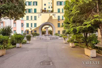 an empty street in front of a building with a fountain at Comfy and Elegant Apartment in Rome