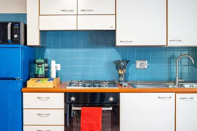 a kitchen with white cabinets and blue tiles at Loft16 Rome - 10 min PlGNETO - COLOSSEO in Rome