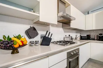 a white kitchen with a bowl of fruit on a counter at Blue Sky Apartment - 5 min Vatican in Rome