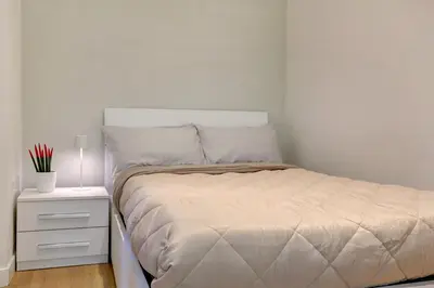 a white bedroom with a bed and a night stand at Porta Pia Suite in Rome